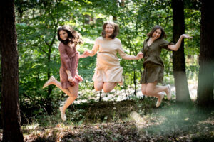 Drei Schwestern im Kleid springen im Wald