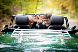 Autoliebhaber Pärchen winkt aus dem Cabrio