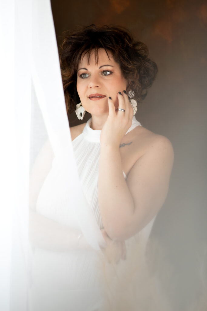 Boudoir Foto einer Frau die aus dem Fenster blickt.