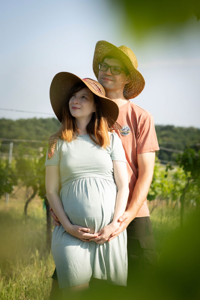 Babybauchshooting in den Weingärten das Paar trägt Sonnenhut