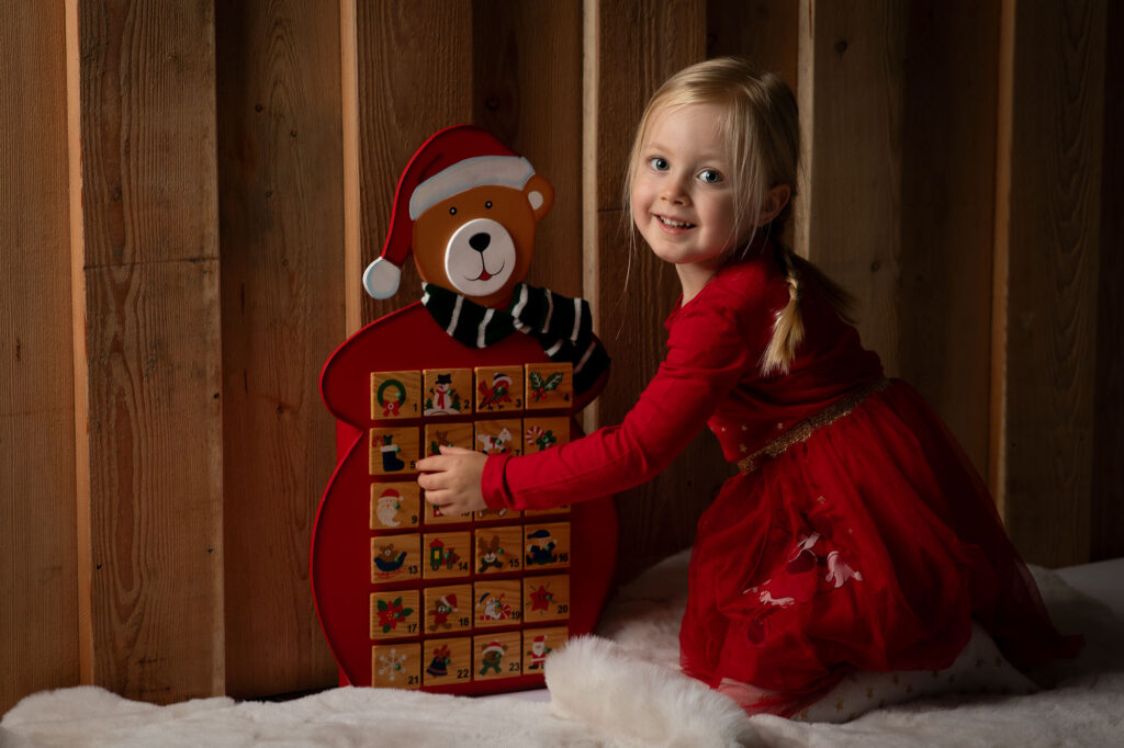 Weihnachtsfotoaktion burgenland das mädchen kniet vor einen Adventkalender im roten Kleid
