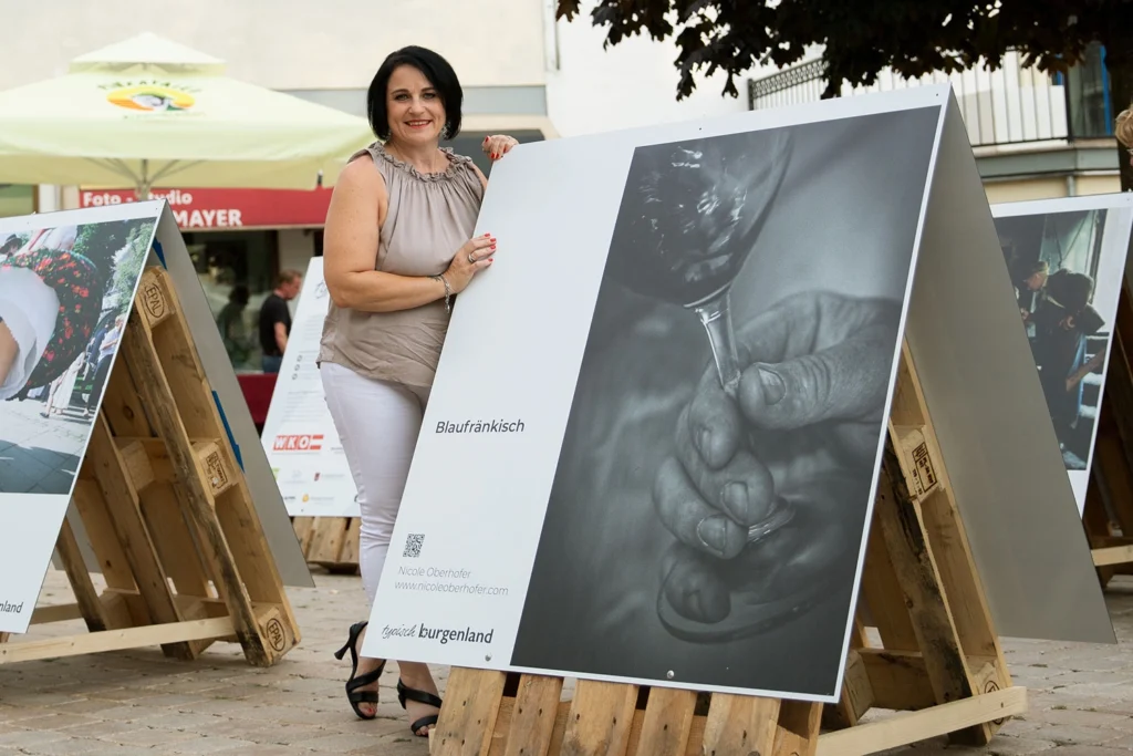 Fotoausstellung typisch burgenland das Foto zeigt nicole bei ihrem bild wo die hand des weinbauers mit einem weinglas zu sehen ist