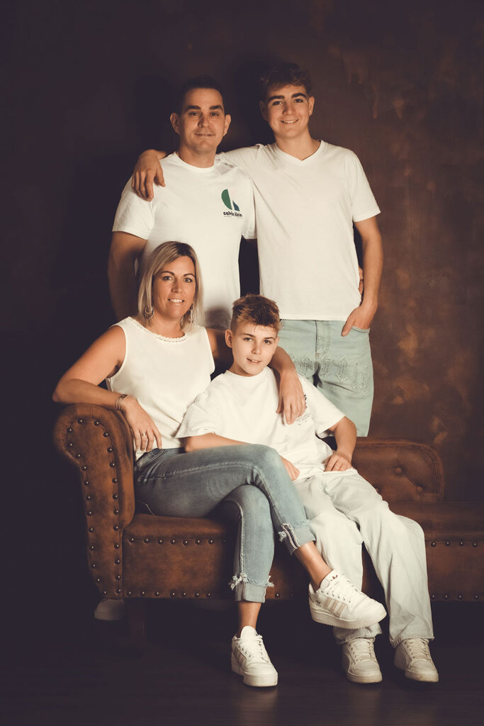 Mutter mit sohn sitz am braunen sofa und älterer Sohn umarmt seinen Vater und stehen dahinter vor einer rostigen