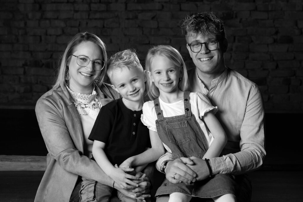 Eltern mit Kindern kuschelt sich zusammen im hintergrund eine backsteinmauer